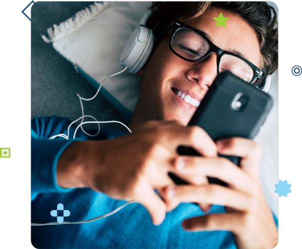Man laying down with headphones on, looking at his smart phone.